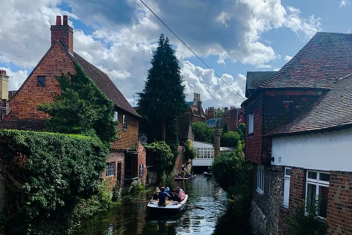 People enjoying a small boat ride on a narrow canal between historic buildings.