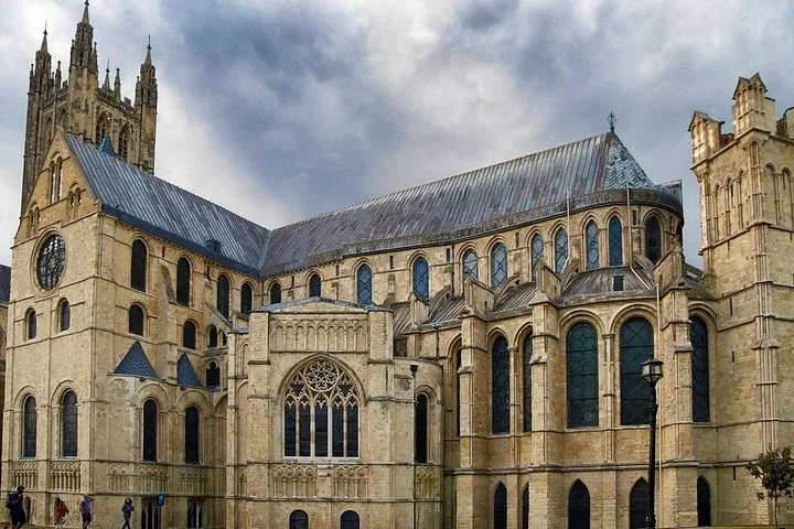 Large, ornate historic stone cathedral with intricate windows under a cloudy sky.