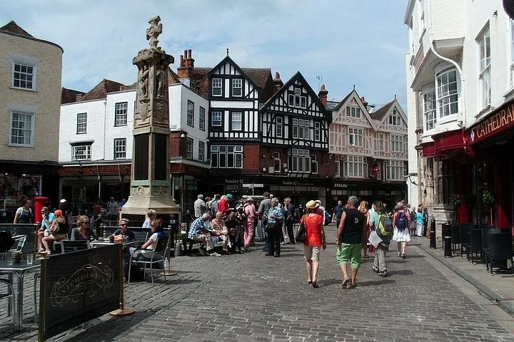 People walking around a bustling historic town square with a monument