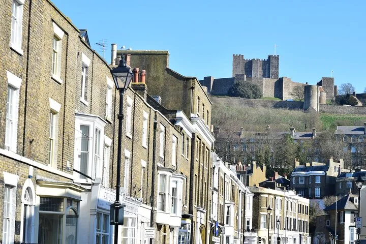 Town street with historic buildings and Dover Castle on the distant hill