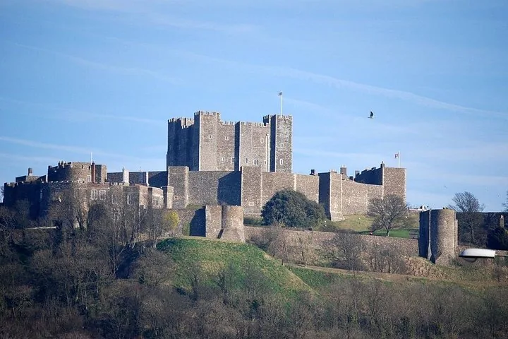 Large medieval castle structure with fortified stone walls on a grassy hill