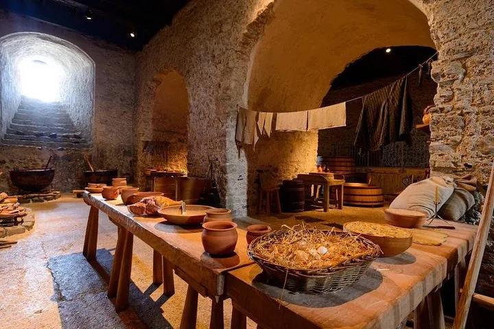 Historic underground castle kitchen with wooden tables and various cooking pots